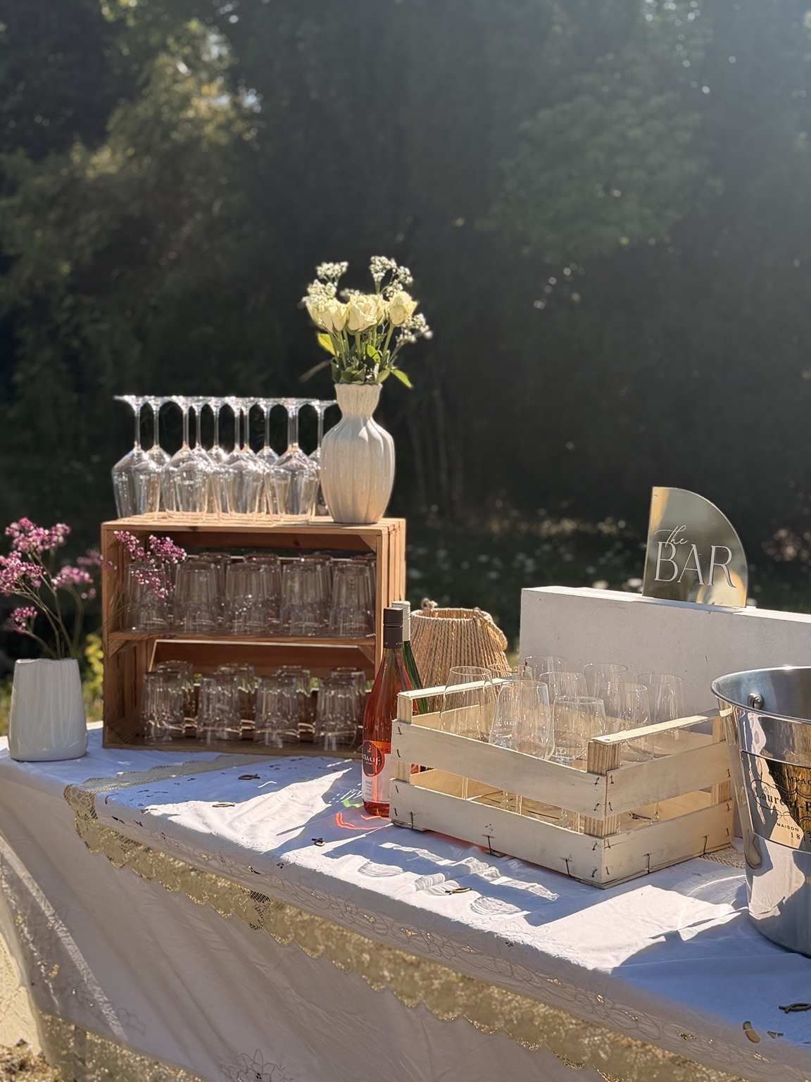 Eventbar mit Gläsern, Blumen und Getränken im Freien